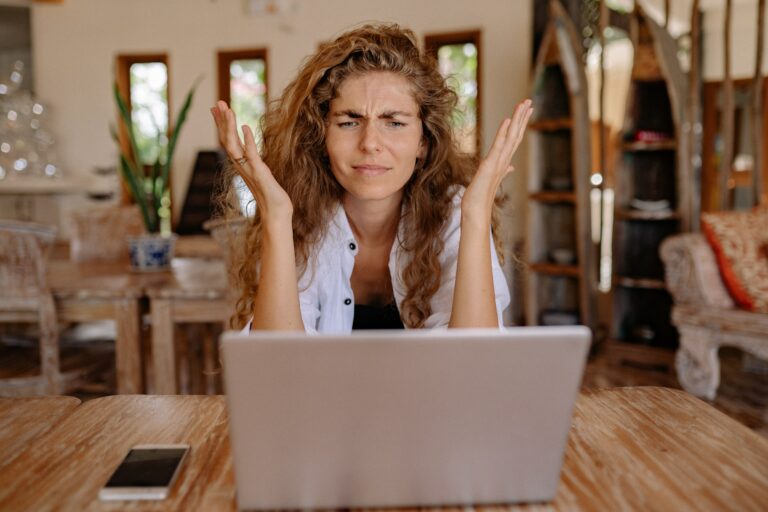 A woman, presumably an Amazon seller, throws up her hands in confusion and frustration as she stares at her computer screen. She doesn't understand why her account has been suspended.