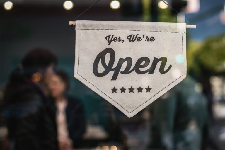 A small business with a sign posted on the front door that reads, "Yes, we're open."